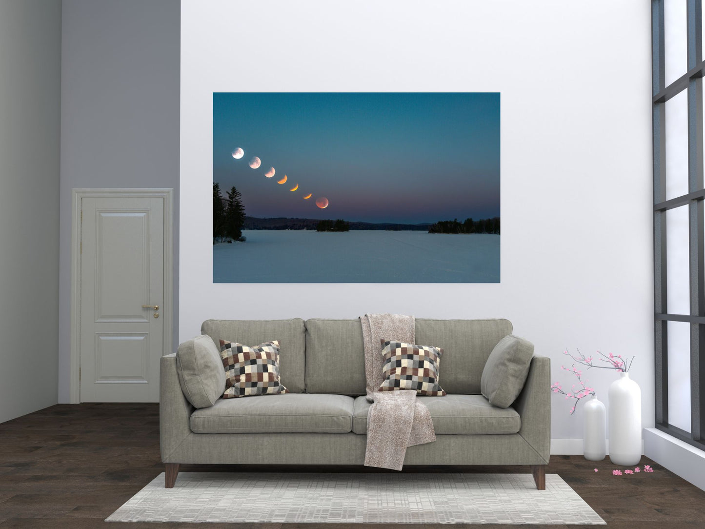 Gray sofa with decorative pillows in a living room setting, featuring a wall art of a lunar eclipse.