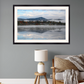 A framed landscape art print of a misty mountain lake scene, displayed on a gray wall above a sofa in a modern living room setting.