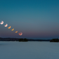 Phases of a lunar eclipse over a snowy landscape with trees.